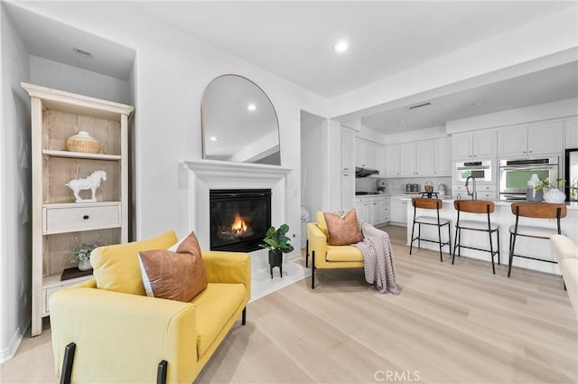 97 Twin Gables, Irvine, CA 92620 - living area with a glass covered fireplace, light wood-type flooring, and recessed lighting