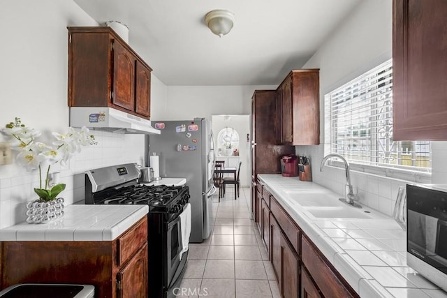 2946 Missouri Ave, South Gate, CA 90280 - kitchen featuring stainless steel appliances, under cabinet range hood, tile counters, and a sink