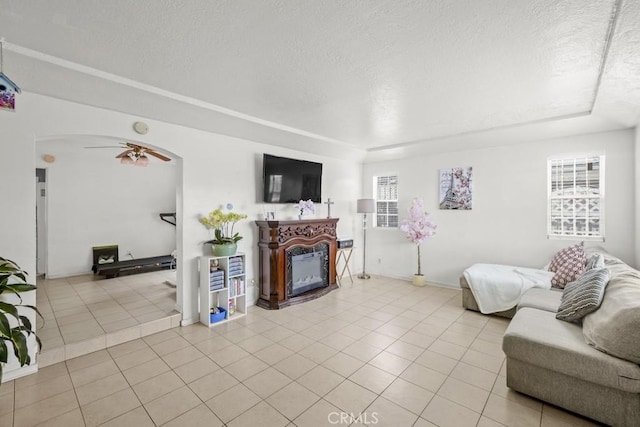 2946 Missouri Ave, South Gate, CA 90280 - living room featuring a textured ceiling, a ceiling fan, light tile patterned floors, a glass covered fireplace, and arched walkways