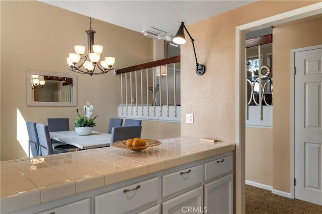 23801 Birch Ln, Mission Viejo, CA 92691 - kitchen with a chandelier, dark colored carpet, white cabinets, and decorative light fixtures