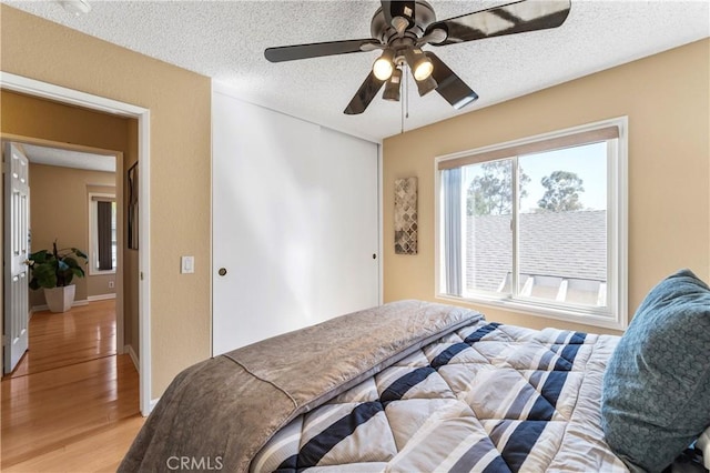23801 Birch Ln, Mission Viejo, CA 92691 - bedroom with light wood-type flooring, a closet, a textured ceiling, baseboards, and a ceiling fan