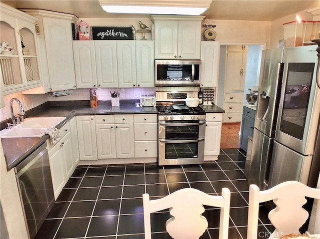 251 W Markland Dr, Monterey Park, CA 91754 - kitchen with appliances with stainless steel finishes, dark countertops, a sink, dark tile patterned flooring, and glass insert cabinets