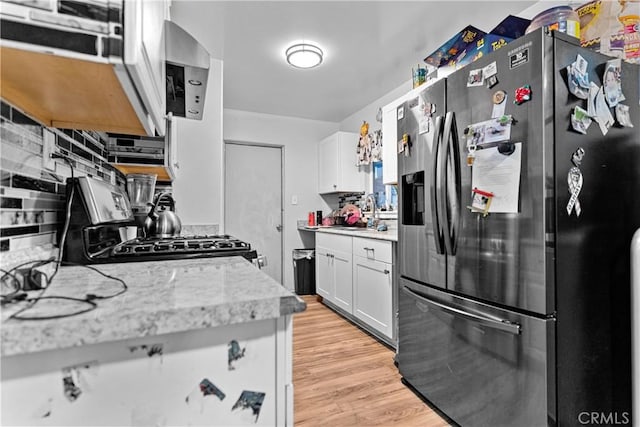4776 E Lowe Ave, Fresno, CA 93702 - kitchen featuring stainless steel refrigerator with ice dispenser, black gas range, light countertops, a sink, and white cabinetry
