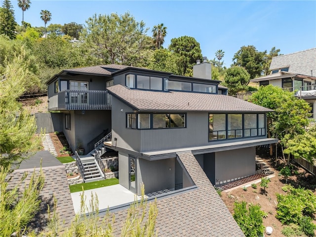 1450 Terrace Way, Laguna Beach, CA 92651 - view of front facade featuring a balcony, a chimney, a shingled roof, and stairs