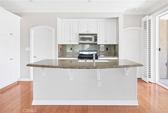 243 Firestone, Hemet, CA 92545 - kitchen with stainless steel microwave, range with gas stovetop, a sink, dark stone counters, and ornamental molding