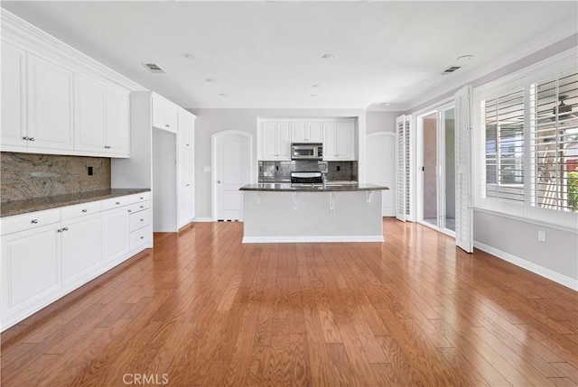 243 Firestone, Hemet, CA 92545 - kitchen featuring stainless steel microwave, dark countertops, backsplash, baseboards, and white cabinetry