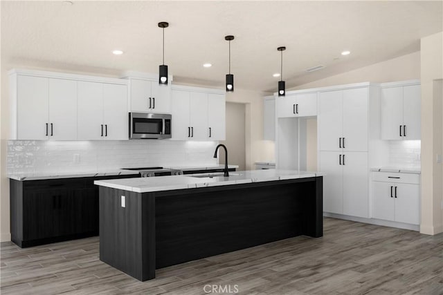 9641 Buena Vista St, Apple Valley, CA 92308 - kitchen with a sink, stainless steel microwave, a kitchen island with sink, decorative backsplash, and light wood-type flooring