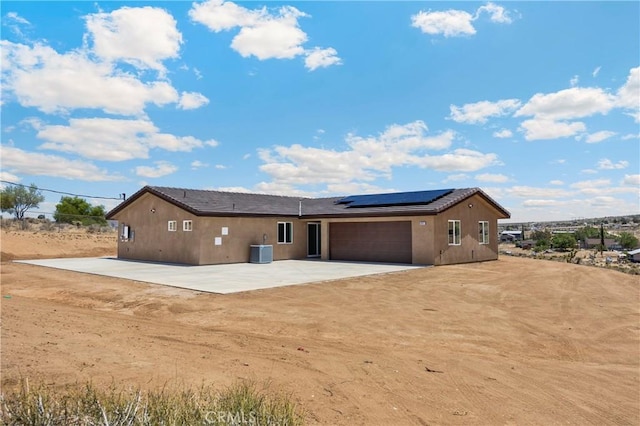 9641 Buena Vista St, Apple Valley, CA 92308 - back of property featuring driveway, roof mounted solar panels, an attached garage, central AC, and stucco siding