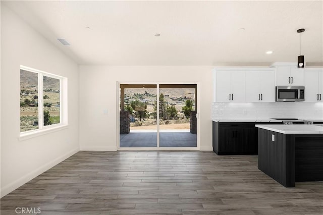 9641 Buena Vista St, Apple Valley, CA 92308 - kitchen with stainless steel microwave, light countertops, white cabinetry, decorative backsplash, and wood finished floors