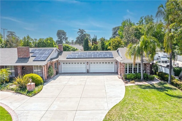 3152 Parkside Dr, San Bernardino, CA 92404 - view of front of property featuring an attached garage, concrete driveway, brick siding, a front yard, and roof mounted solar panels