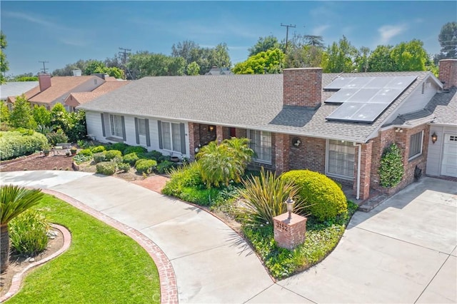 3152 Parkside Dr, San Bernardino, CA 92404 - view of front of property featuring a chimney, brick siding, solar panels, a shingled roof, and concrete driveway