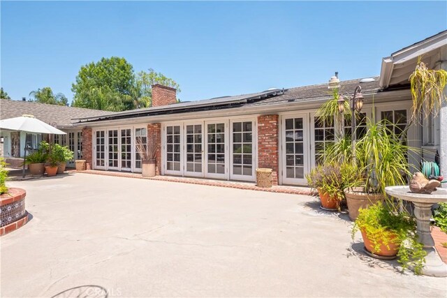 3152 Parkside Dr, San Bernardino, CA 92404 - back of house with a patio, a chimney, brick siding, and roof mounted solar panels