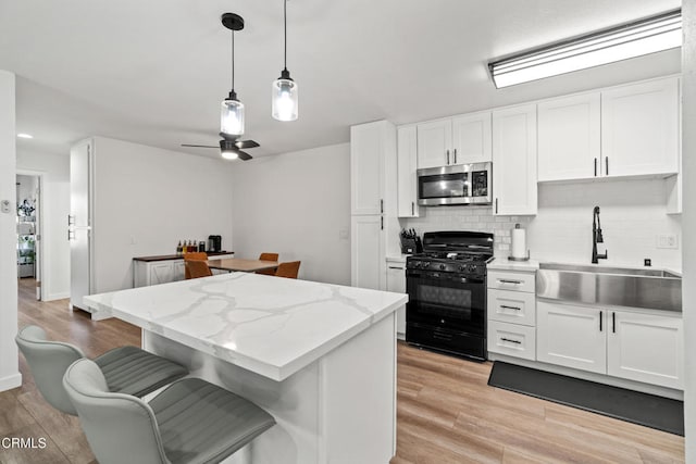 205 W Channel Islands Blvd, Port Hueneme, CA 93041 - kitchen featuring stainless steel microwave, black gas stove, a sink, a center island, and decorative backsplash