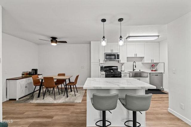 205 W Channel Islands Blvd, Port Hueneme, CA 93041 - kitchen featuring stainless steel appliances, a sink, white cabinetry, baseboards, and light wood-style floors