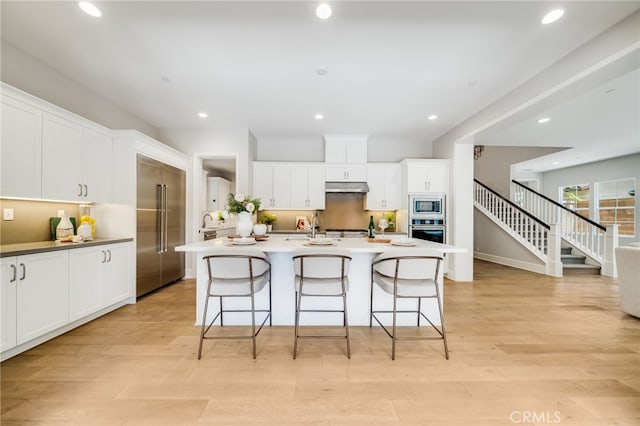 126 Paxton, Irvine, CA 92620 - kitchen featuring appliances with stainless steel finishes, under cabinet range hood, a kitchen bar, a center island with sink, and recessed lighting