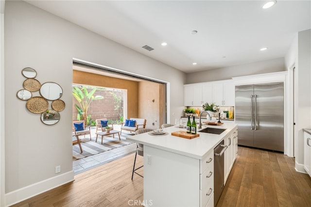 126 Paxton, Irvine, CA 92620 - kitchen with appliances with stainless steel finishes, hardwood / wood-style floors, an island with sink, white cabinetry, and light countertops
