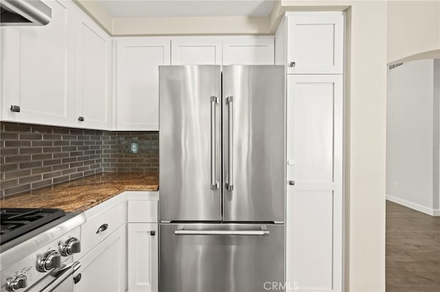 27054 Riversbridge Way, Valencia, CA 91354 - kitchen featuring appliances with stainless steel finishes, exhaust hood, decorative backsplash, white cabinets, and dark stone countertops