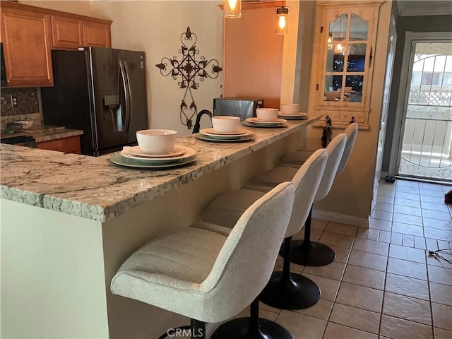 17911 Juniper St, Adelanto, CA 92301 - kitchen with black fridge, ornamental molding, a kitchen bar, decorative backsplash, and baseboards
