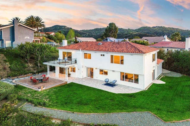 4400 Chaumont Rd, Woodland Hills, CA 91364 - back of property at dusk featuring a balcony, a patio, a yard, and a tiled roof