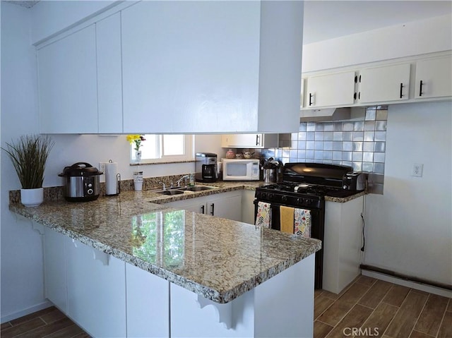 15043 S Culver Rd, Victorville, CA 92394 - kitchen featuring a sink, white microwave, a peninsula, wood finish floors, and black range with gas cooktop