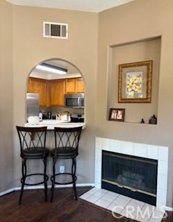 39244 Turtle Bay Ln Unit F, Murrieta, CA 92563 - kitchen featuring stainless steel microwave, freestanding refrigerator, a kitchen bar, a tile fireplace, and a peninsula