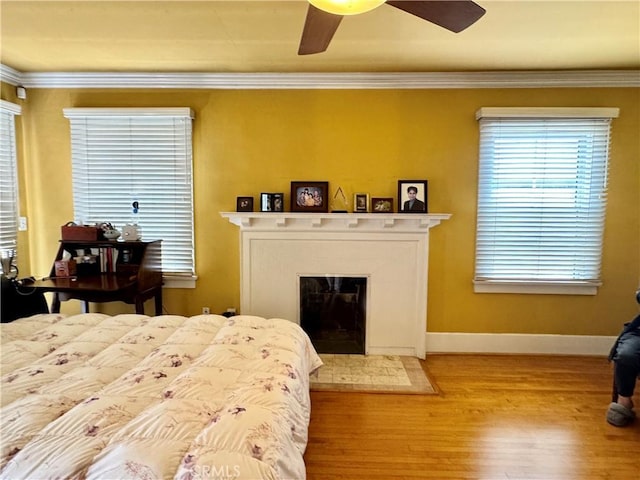 867 S Bronson Ave, Los Angeles, CA 90005 - bedroom with wood finished floors, crown molding, a glass covered fireplace, baseboards, and a ceiling fan