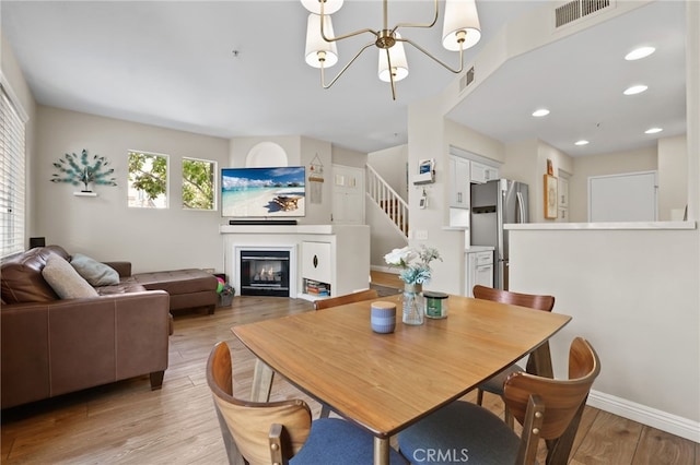2348 Sunningdale Dr, Tustin, CA 92782 - dining space featuring a chandelier, light wood finished floors, a glass covered fireplace, recessed lighting, and stairway