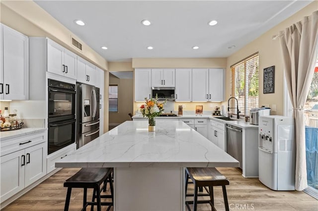 28436 Calex Dr, Valencia, CA 91354 - kitchen featuring appliances with stainless steel finishes, a sink, a breakfast bar, light wood finished floors, and a kitchen island