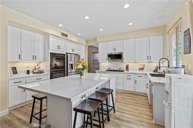 28436 Calex Dr, Valencia, CA 91354 - kitchen featuring stainless steel appliances, a kitchen bar, light wood-style flooring, light stone counters, and a kitchen island