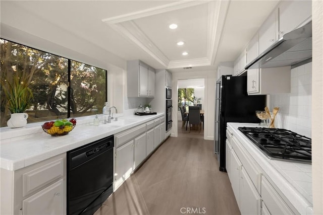 5622 Revere Ave, Rancho Cucamonga, CA 91737 - kitchen featuring black appliances, tile counters, a tray ceiling, under cabinet range hood, and ornamental molding