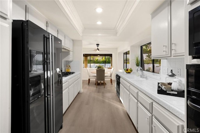 5622 Revere Ave, Rancho Cucamonga, CA 91737 - kitchen with black appliances, a tray ceiling, ornamental molding, ceiling fan, and light wood-style flooring