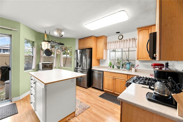 1784 Promenade Pl, Vista, CA 92083 - kitchen featuring stainless steel appliances, light countertops, light wood-style floors, a center island, and a sink