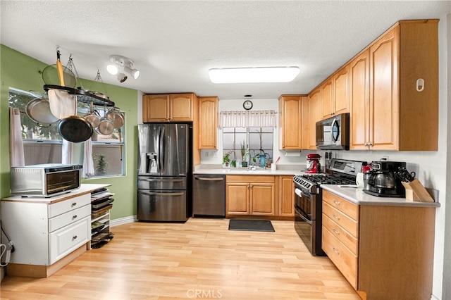 1784 Promenade Pl, Vista, CA 92083 - kitchen featuring appliances with stainless steel finishes, light wood-style flooring, light countertops, a textured ceiling, and a sink