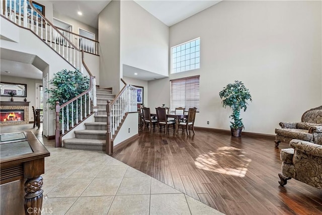 3582 Cedar Ridge Ln, Corona, CA 92881 - entryway with a towering ceiling, stairway, a glass covered fireplace, wood finished floors, and baseboards