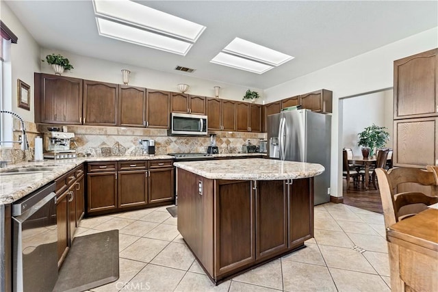 3582 Cedar Ridge Ln, Corona, CA 92881 - kitchen with stainless steel appliances, a sink, light tile patterned flooring, backsplash, and a skylight