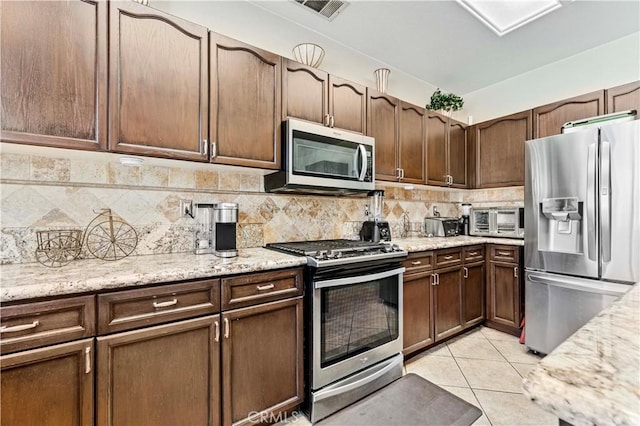 3582 Cedar Ridge Ln, Corona, CA 92881 - kitchen with stainless steel appliances, tasteful backsplash, light tile patterned floors, light stone counters, and dark brown cabinets