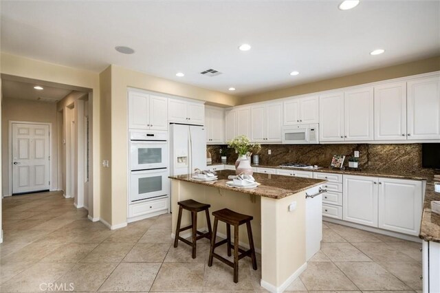 33850 Sattui St, Temecula, CA 92592 - kitchen featuring white appliances, tasteful backsplash, white cabinets, dark stone counters, and recessed lighting