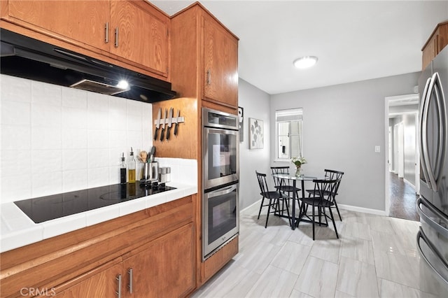 15113 Hayford St, La Mirada, CA 90638 - kitchen featuring tile counters, stainless steel appliances, brown cabinets, and under cabinet range hood