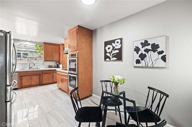 15113 Hayford St, La Mirada, CA 90638 - kitchen with stainless steel appliances, brown cabinetry, light countertops, a sink, and baseboards
