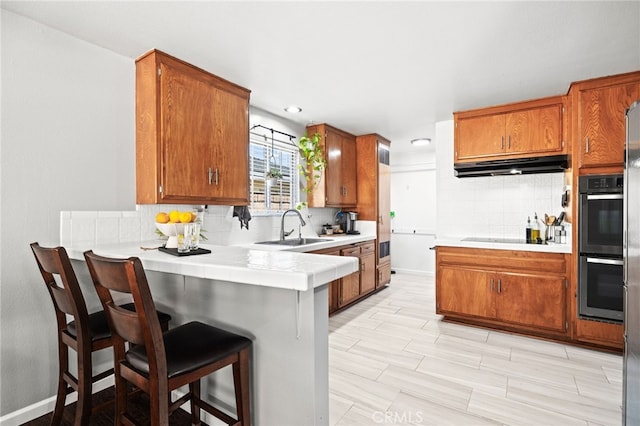 15113 Hayford St, La Mirada, CA 90638 - kitchen with under cabinet range hood, a sink, brown cabinets, backsplash, and recessed lighting