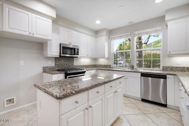 5611 Dorsey St, Ventura, CA 93003 - kitchen with appliances with stainless steel finishes, a center island, light tile patterned floors, light stone counters, and white cabinets