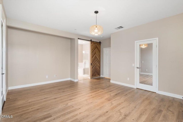5611 Dorsey St, Ventura, CA 93003 - unfurnished bedroom with light wood finished floors, a barn door, and connected bathroom