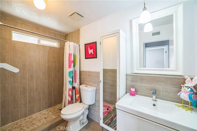 6114 Sard St, Rancho Cucamonga, CA 91701 - bathroom featuring toilet, tiled shower, tile walls, and vanity