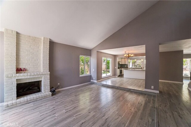 6114 Sard St, Rancho Cucamonga, CA 91701 - unfurnished living room with high vaulted ceiling, a chandelier, wood finished floors, a brick fireplace, and baseboards