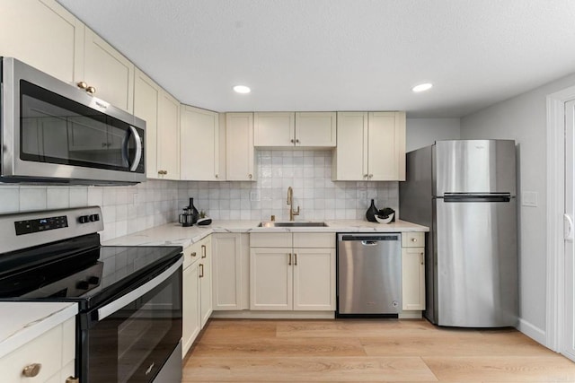 4532 Dawson Ave Unit 3, San Diego, CA 92115 - kitchen with appliances with stainless steel finishes, a sink, tasteful backsplash, light wood-type flooring, and light stone counters