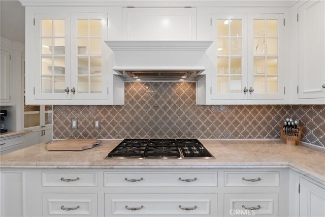 72408 Desert Dr, Rancho Mirage, CA 92270 - kitchen featuring stainless steel gas stovetop, white cabinetry, glass insert cabinets, decorative backsplash, and light stone counters