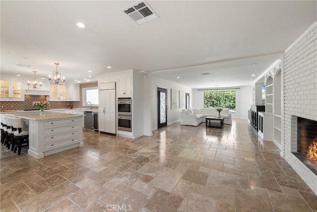 72408 Desert Dr, Rancho Mirage, CA 92270 - kitchen featuring stone tile flooring, open floor plan, a fireplace, light countertops, and white cabinetry