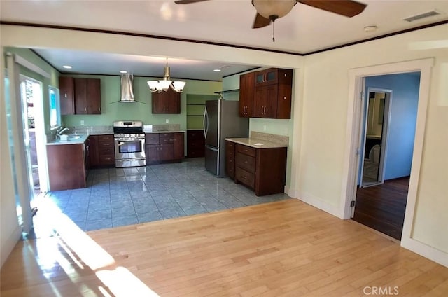 3513 Denker Ave, Los Angeles, CA 90018 - kitchen with appliances with stainless steel finishes, wall chimney exhaust hood, light countertops, ceiling fan, and ornamental molding