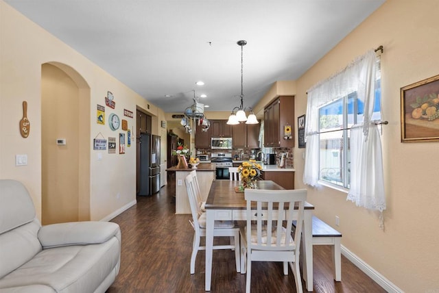 31081 Bunker Dr, Temecula, CA 92591 - dining area featuring dark wood-style flooring, baseboards, arched walkways, recessed lighting, and a chandelier