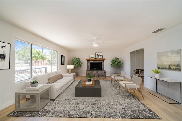 28732 Paseo Diablo, Menifee, CA 92587 - living area featuring light wood-style floors, ceiling fan, a fireplace with raised hearth, and baseboards